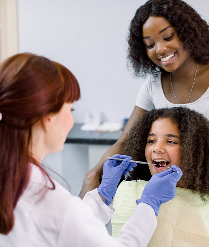 Dentist examining child's smile during pediatric dentistry visit