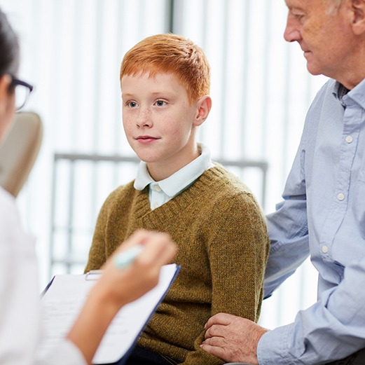 a pediatric dentist speaking with a boy and his father
