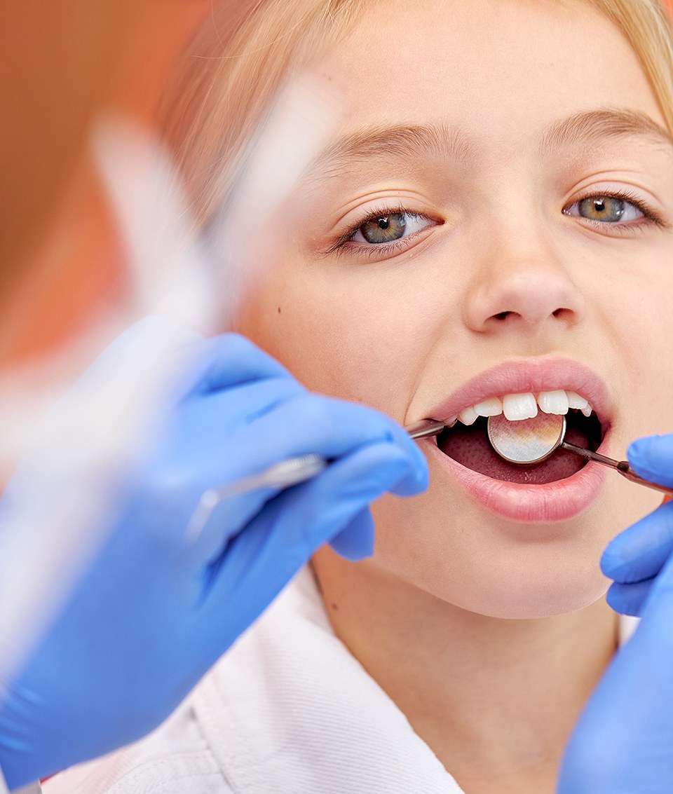 Little girl having her teeth checked by dentist 