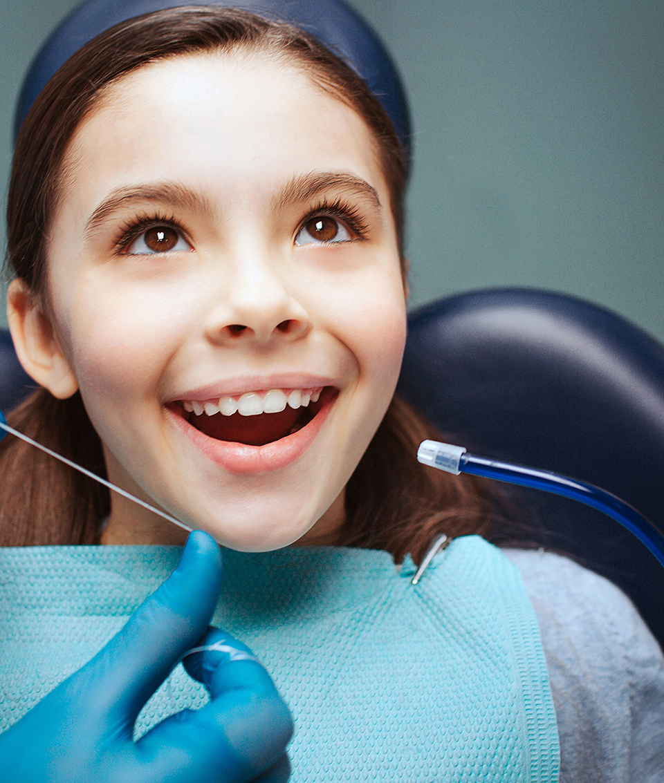 Dentist preparing to floss little girl’s teeth