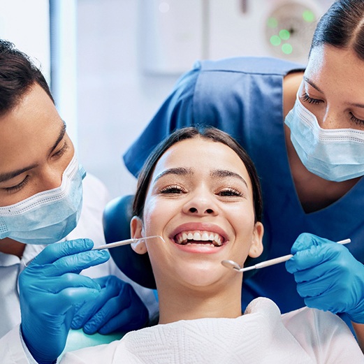 Dentist and hygienist alongside female patient