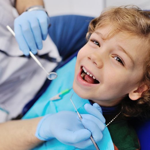 a child patient smiling while receiving dental sealants